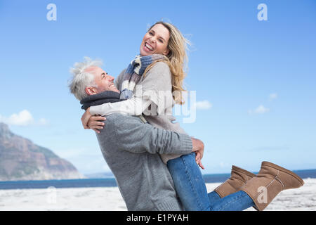 Smiling couple having fun on the beach in warm clothing Stock Photo