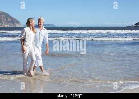 Happy couple walking barefoot on the beach Stock Photo