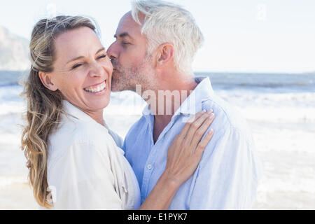 Man kissing his smiling partner on the cheek at the beach Stock Photo