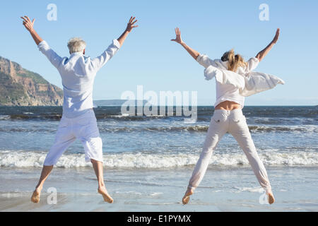 Couple jumping on the beach together Stock Photo