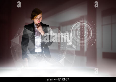 Composite image of redhead businesswoman using interactive desk Stock Photo
