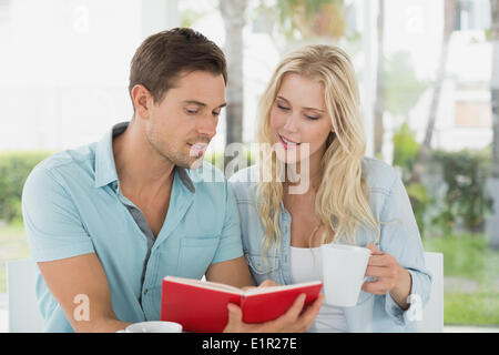 Hip young couple having coffee together reading book Stock Photo