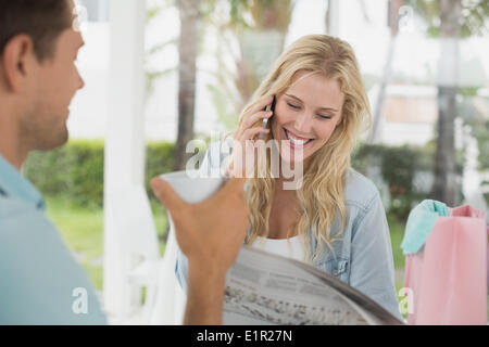 Pretty blonde talking on phone while having coffee with boyfriend Stock Photo