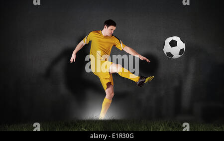 Composite image of football player in yellow kicking Stock Photo