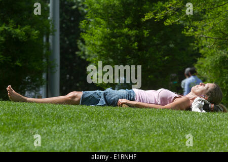 London, UK. 9th June 2014. A woman sunbathing on the grass as the warm weather  and  summer finally arrives Credit:  amer ghazzal/Alamy Live News Stock Photo