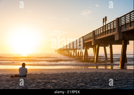 Young woman silently soaking in the beauty and wonder of a dramatic sunrise at Jacksonville Beach, Florida, USA. Stock Photo