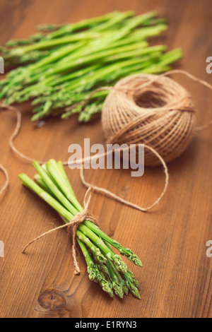 Bundle of green asparagus and a coil of rope on the table. Shallow depth of field Stock Photo