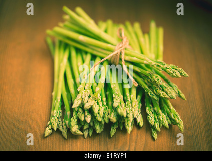 Sprouts of green asparagus on the table. Shallow depth of field. Vintage tonning. Stock Photo
