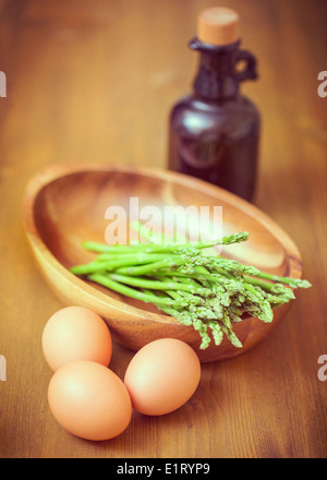 Green asparagus in a bowl, eggs and oil bottle. Shallow depth of field Stock Photo