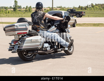 Man on Harley Davidson Motorcycle wearing leather vest with Harley Davidson logo Stock Photo