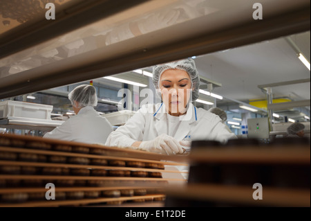 Workers at the Swiss chocolate factory of Lindt & Spruengli in Zurich / Kilchberg are sorting and packaging chocolate candies. Stock Photo