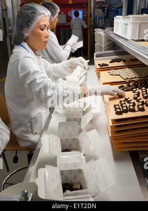 Workers at the Swiss chocolate factory of Lindt & Spruengli in Zurich / Kilchberg are sorting and packaging chocolate candies. Stock Photo