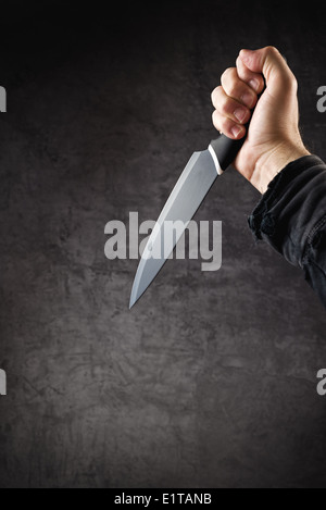 Hand with shiny knife - a killer person with sharp knife about to commit a homicide, murder scenery. Stock Photo