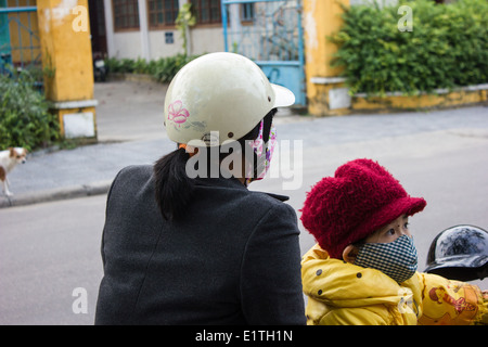 Woman and young child on a motorbike in the old town of Hoi An in Vietnam. Stock Photo