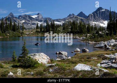 Backpacker rafting Gwillim Lakes, Selkirk Mountains, Valhalla Provincial Park, British Columbia, Canada Stock Photo