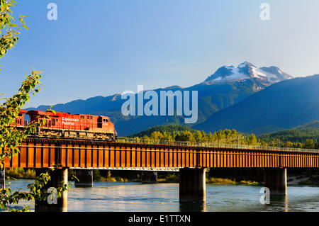 A Canadian Pacific Rail locomotive crosses the rail bridge over the Columbia River in Revelstoke, BC Stock Photo