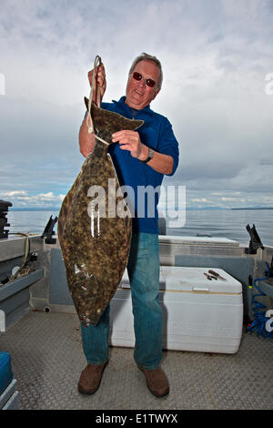 Senior retired man holding proud a halibut which he just caught on a small fishing boat off Northern Vancouver Island in British