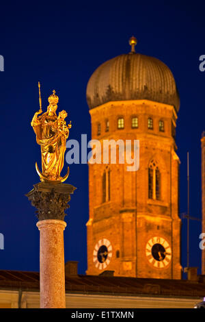 Golden statue the Virgin Mary atop the Mariensäule in the Marienplatz with a tower the Frauenkirche (Cathedral our Blessed Stock Photo