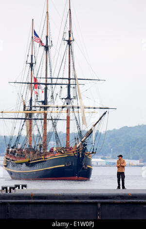As a man watches the festivities, sailing ship Bounty navigates Halifax Harbour during the Parade of Sail conclusion of the 2007 Stock Photo