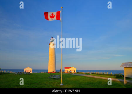 Cap-des-Rosiers Lighthouse at the entrance of the Gulf of St. Lawrence, Quebec, Canada and Canadian flag Stock Photo