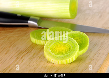 Fresh leek whole and sliced on a wooden board with knife Stock Photo