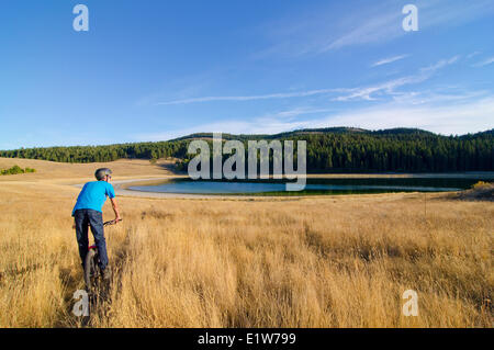 Young mountain biker rides towards unknown lake near Merritt in the Nicola Valley region of British Columbia, Canada