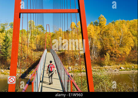 Hiker crosses a bridge over the Whiteshell River along the Trans Canada Trail, Whiteshell Provincial Park, Manitoba, Canada Stock Photo