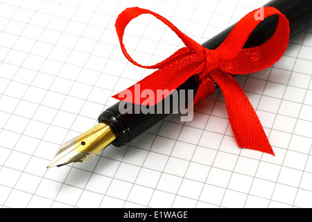 Fountain pen on the notepad with red bow close-up Stock Photo