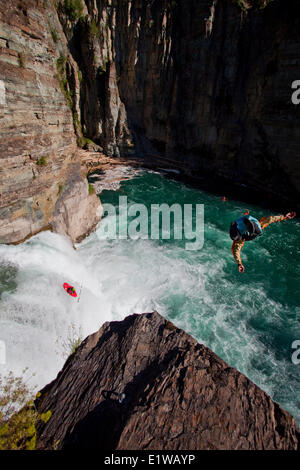 A male kayaker runs leap of faith, a 30 foot waterfall while a cliff jumper jumps from 70ft on the Upper Elk River, Fernie, BC Stock Photo