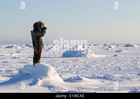 Inuit man scanning ice for polar bears, west coast Hudson Bay, south of Arviat, Nunavut, Canada Stock Photo