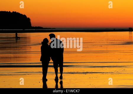 A young couple at sunset about to kiss while on Chesterman Beach near Tofino, BC. Stock Photo