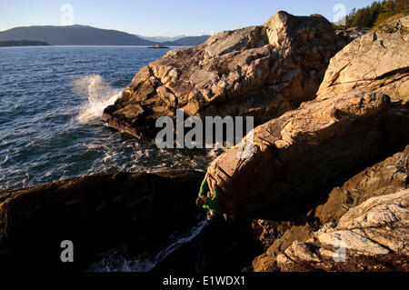 Rock climbing above the ocean at Lighthouse Park. West Vancouver, British Columbia, Canada Stock Photo