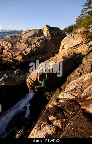Rock climbing above the ocean at Lighthouse Park. West Vancouver, British Columbia, Canada Stock Photo