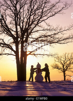 mother and daughter make a snowman, Birds Hill Provincial Park, Manitoba, Canada Stock Photo