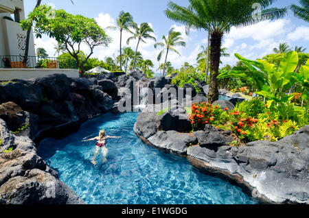 A woman relaxes in the swimming pool at the Grand Hyatt Hotel, Kaua'i Stock Photo