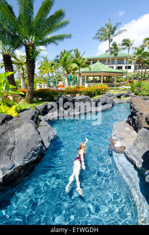 A woman relaxes in the swimming pool at the Grand Hyatt Hotel, Kaua'i Stock Photo