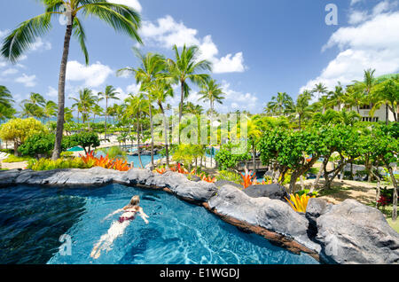 A woman relaxes in the swimming pool at the Grand Hyatt Hotel, Kaua'i Stock Photo