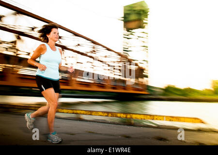 Attractive woman in her 50's jogging on an urban trail. Stock Photo