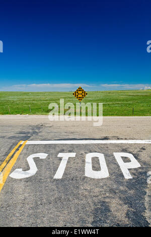 Stop sign painted on rural road with direction sign, south Alberta, Canada. Stock Photo