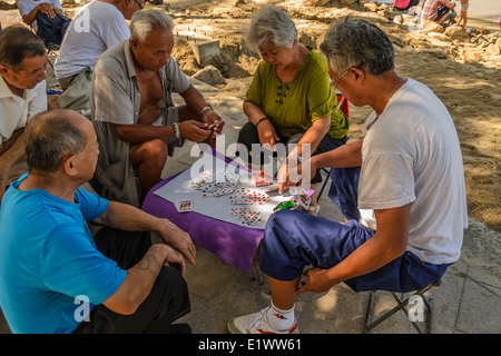 Some old people playing mahjong on the summer beach. Stock Photo