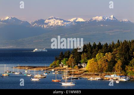 Boats anchored in the bay by Protection Island near Nanaimo BC.  The BC Ferry Queen Cowichan sails to Vancouver with the Stock Photo