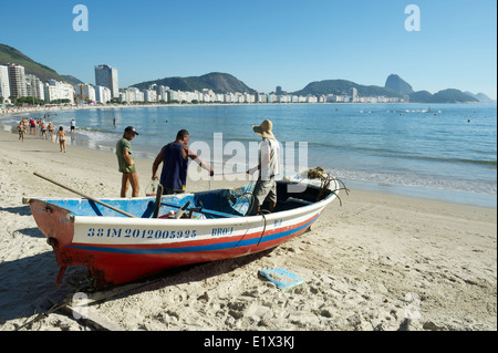 RIO DE JANEIRO, BRAZIL - FEBRUARY 3, 2014: Brazilian fishermen work from a brightly painted boat on Copacabana Beach. Stock Photo