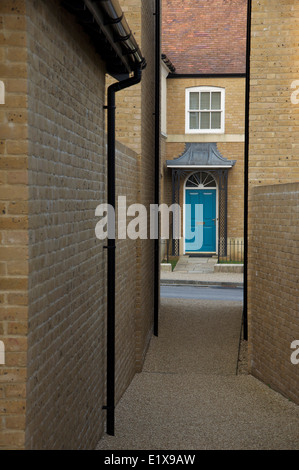 Modern  architecture. A narrow alley between two houses opens onto a street and frames the front door of a house opposite. Poundbury, Dorchester, UK. Stock Photo