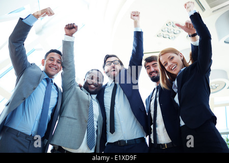 Group of ecstatic business partners looking at camera with raised arms Stock Photo