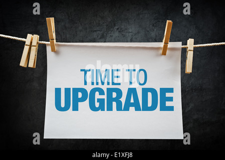 Time to upgrade message printed on paper attached to rope with clothespins. Stock Photo