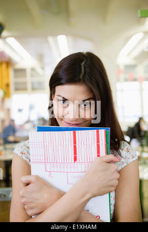 Portrait of happy young businesswoman with books in office Stock Photo