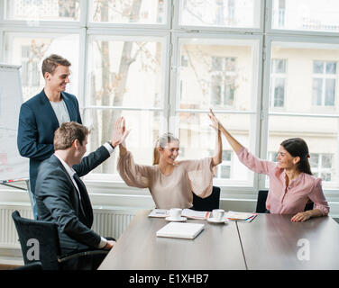 Young business team doing high five at conference table Stock Photo