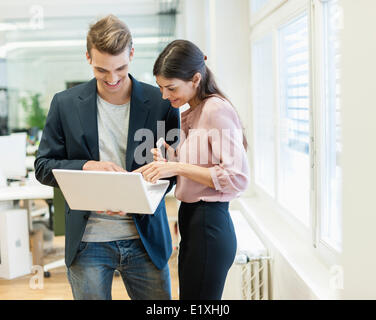 Young businessman and businesswoman using laptop in office Stock Photo