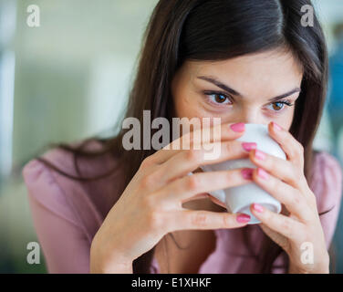 Young businesswoman having coffee in office Stock Photo