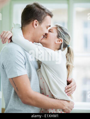 Loving couple kissing while hugging in house Stock Photo